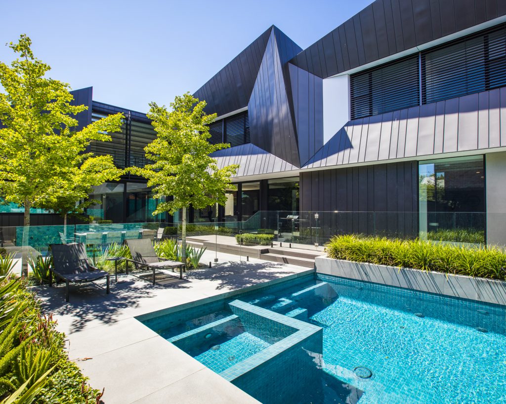 A Bayside, Victoria, landscape design by Ian Barker Gardens. The pool is the feature with Gingko biloba trees in the cut outs in the paving, outside of the glass pool fence.
