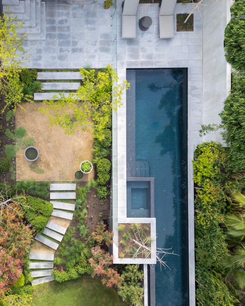 An Ian Barker Garden design in Hawthorn, named Hawthorn Hills. The entertaining terrace was set against a twenty-metre lap pool and burnished concrete steppers, with the surrounding planting built around an existing mature Eucalyptus camaldulensis already anchoring the block. The garden's age and grain did the work that a blank canvas never could - established trees, a change in level, and an existing outbuilding are assets, not obstacles to clear. So the entertaining area belongs next to the home, at the top of the slope, inviting you into each level of the pool, steps, lawn, and gravel areas below.